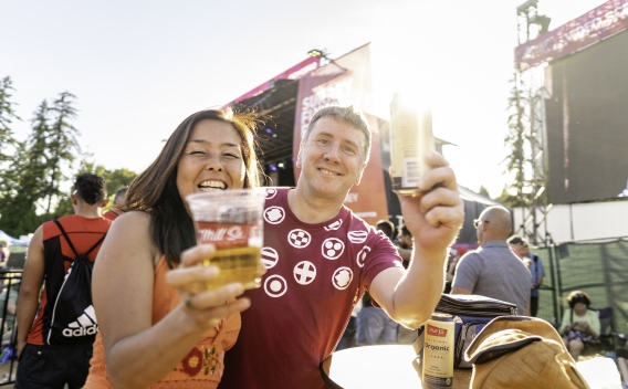 Smiling couple hold up two drinks in celebration