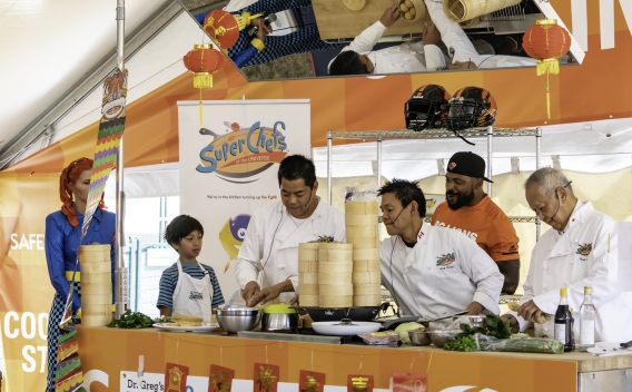 Chefs demonstrate how to make Chinese dumplings while child watches