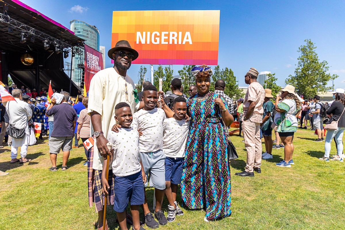 Proud smiling family stands in front of Nigeria sign