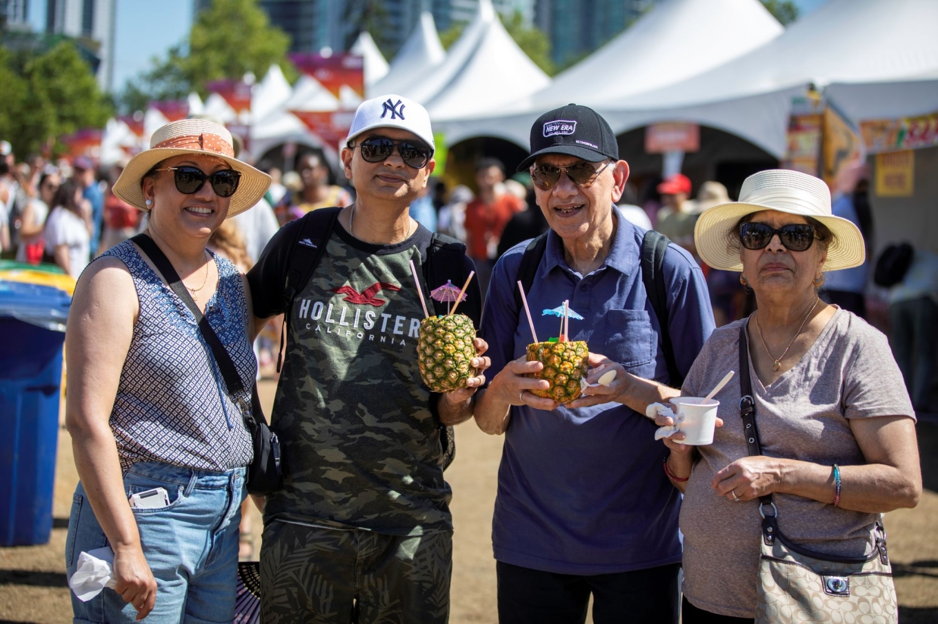 Four people holding pineapple drinks.